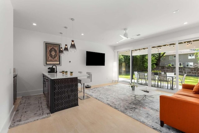 living area featuring wood finished floors, baseboards, recessed lighting, and ceiling fan