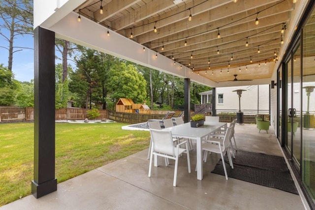 view of patio featuring outdoor dining space, ceiling fan, and view of scattered trees