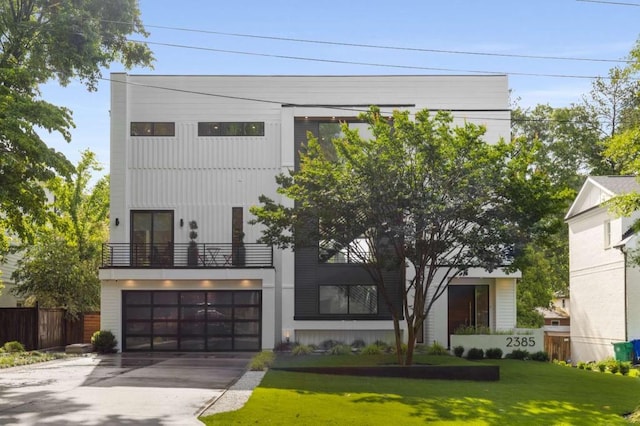 contemporary home with an attached garage, driveway, and a balcony