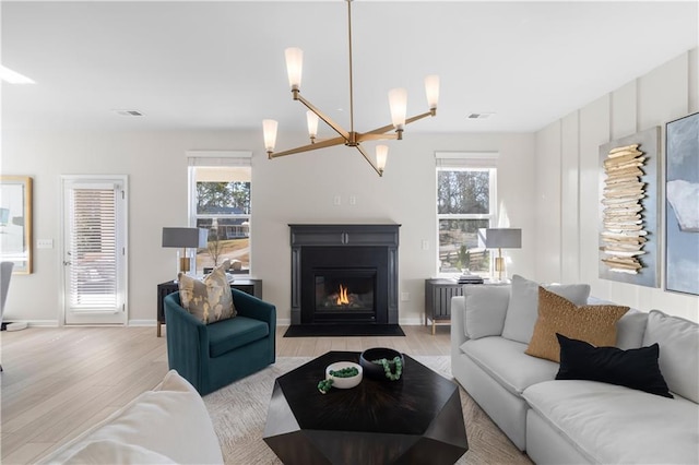 209 Chiswick Loop, Stockbridge, GA 30281 - living room with light wood-style floors, healthy amount of natural light, a fireplace with flush hearth, and a chandelier