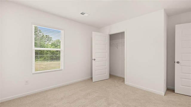 unfurnished bedroom featuring visible vents, baseboards, a closet, and light colored carpet