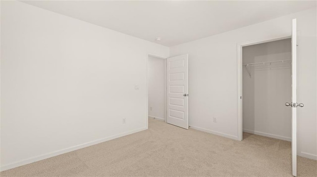 unfurnished bedroom with light carpet, baseboards, and a closet