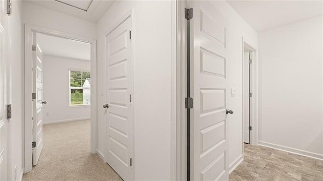 hallway featuring light carpet and baseboards