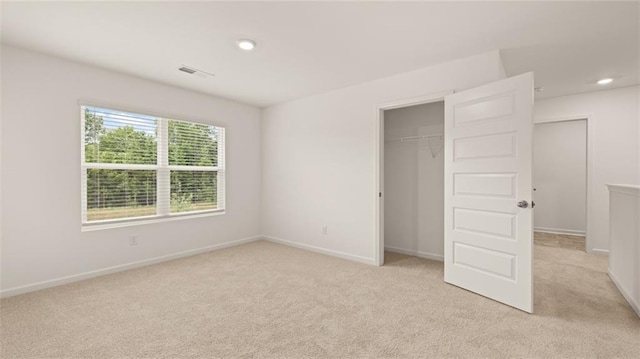 unfurnished bedroom with recessed lighting, a closet, light colored carpet, visible vents, and baseboards