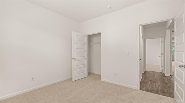 unfurnished bedroom with a closet and light colored carpet