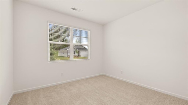 unfurnished room with light carpet, visible vents, and baseboards