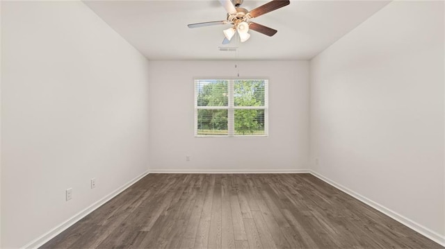 spare room featuring a ceiling fan, dark wood finished floors, visible vents, and baseboards