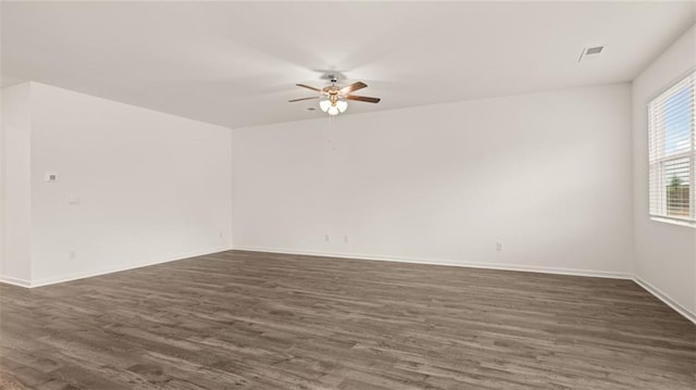 unfurnished room featuring visible vents, dark wood finished floors, baseboards, and ceiling fan