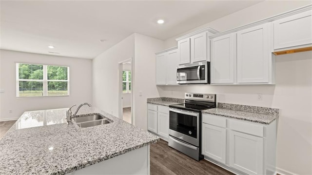 kitchen with light stone counters, dark wood finished floors, appliances with stainless steel finishes, white cabinets, and a sink