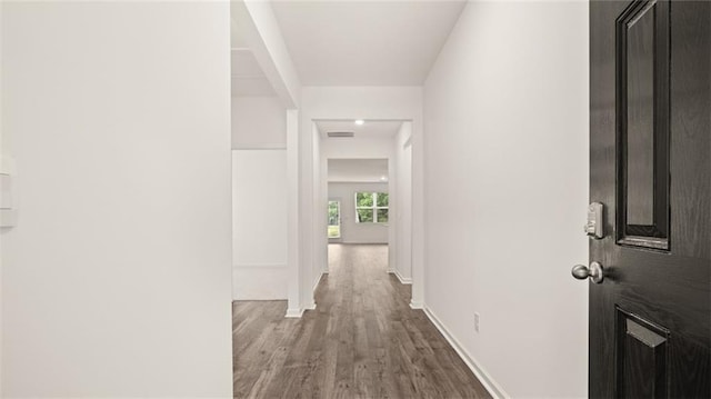 corridor with baseboards and wood finished floors