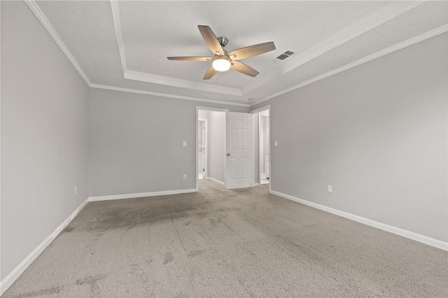 carpeted spare room featuring crown molding, a textured ceiling, a raised ceiling, and baseboards