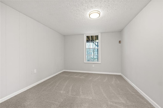 carpeted spare room with baseboards and a textured ceiling