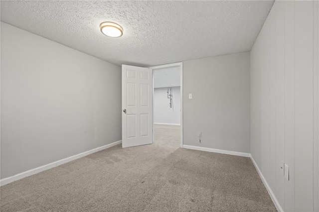 carpeted spare room featuring baseboards and a textured ceiling