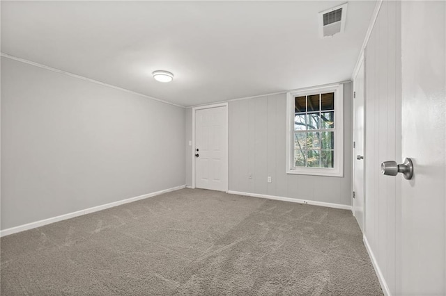 carpeted empty room featuring visible vents, crown molding, and baseboards