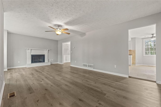 unfurnished living room with a glass covered fireplace, visible vents, and wood finished floors