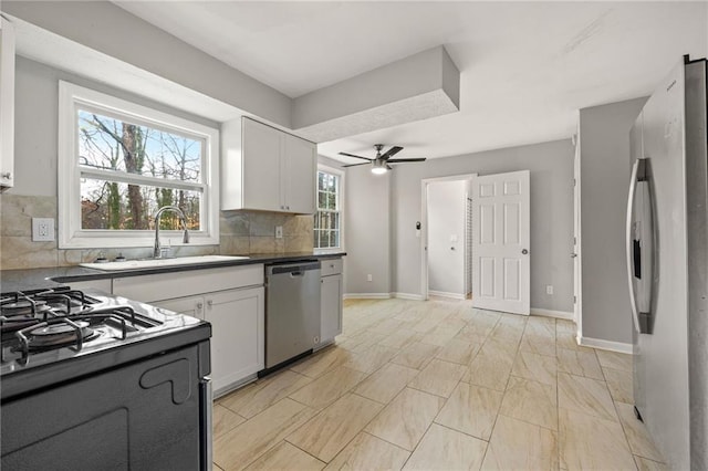 kitchen with a sink, white cabinetry, stainless steel appliances, decorative backsplash, and baseboards