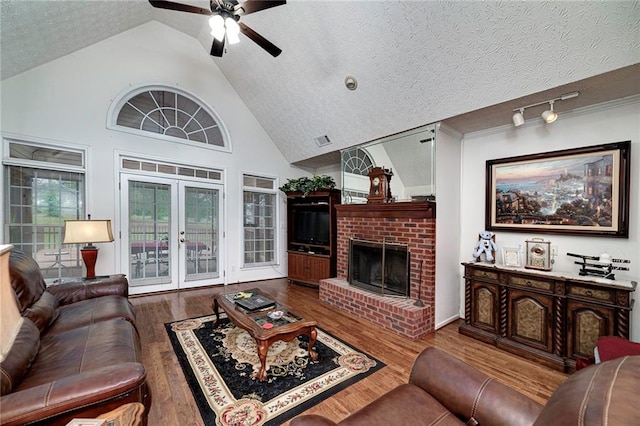 living room featuring dark hardwood / wood-style floors, a textured ceiling, a fireplace, and ceiling fan