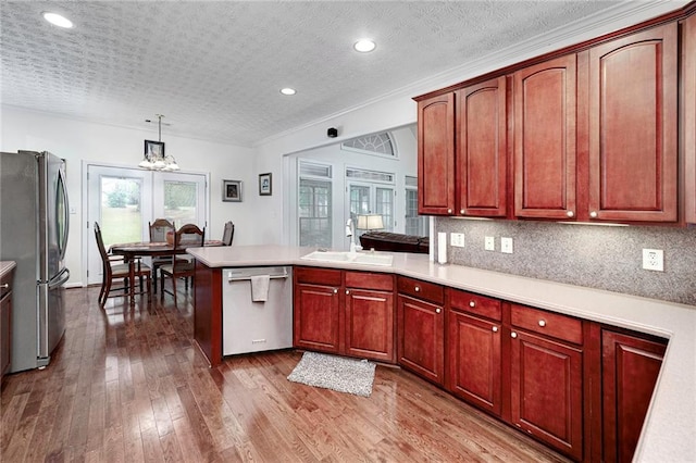 kitchen with an inviting chandelier, appliances with stainless steel finishes, decorative light fixtures, and wood-type flooring