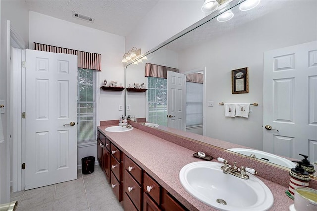 bathroom featuring a textured ceiling, dual bowl vanity, and tile flooring