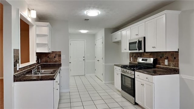 kitchen featuring sink, white cabinets, decorative backsplash, light tile patterned floors, and stainless steel appliances