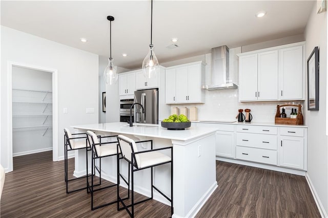 608 Belshire Dr, Acworth, GA 30102 - kitchen featuring wall chimney exhaust hood, appliances with stainless steel finishes, a center island with sink, decorative backsplash, and dark wood-style floors