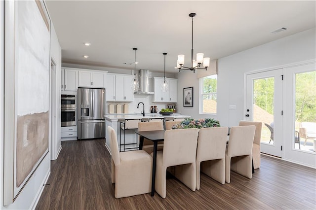 608 Belshire Dr, Acworth, GA 30102 - kitchen featuring appliances with stainless steel finishes, wall chimney exhaust hood, a kitchen island with sink, a chandelier, and dark wood finished floors