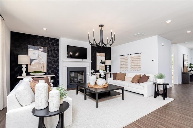 608 Belshire Dr, Acworth, GA 30102 - living room featuring an accent wall, a chandelier, a glass covered fireplace, wood finished floors, and recessed lighting