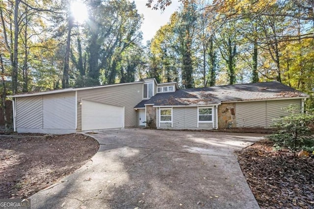 mid-century home featuring concrete driveway and an attached garage