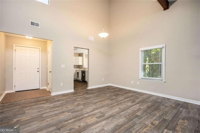 unfurnished living room with a high ceiling, dark wood finished floors, and baseboards