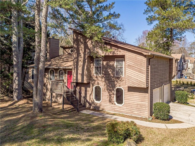 view of front of home with an attached garage, stairs, a front lawn, and concrete driveway