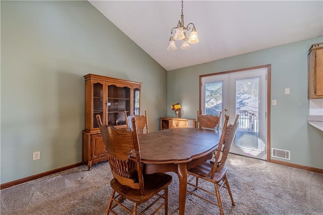 dining room featuring lofted ceiling, a notable chandelier, visible vents, and light colored carpet