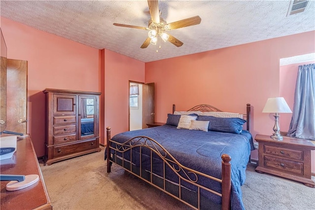 bedroom with a ceiling fan, carpet, visible vents, and a textured ceiling