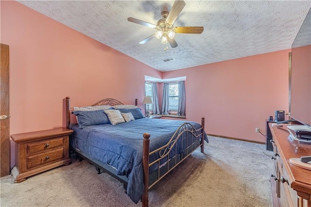 bedroom with ceiling fan, a textured ceiling, light carpet, visible vents, and baseboards