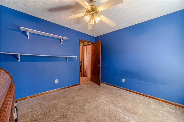 unfurnished bedroom featuring a ceiling fan, carpet, baseboards, and a textured ceiling