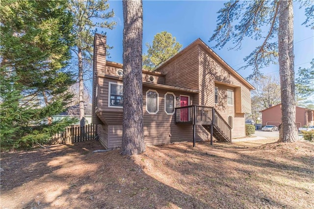 rear view of property featuring stairs, a chimney, and fence