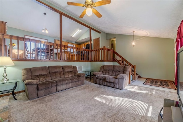 living area featuring ceiling fan, vaulted ceiling with beams, carpet flooring, visible vents, and stairs