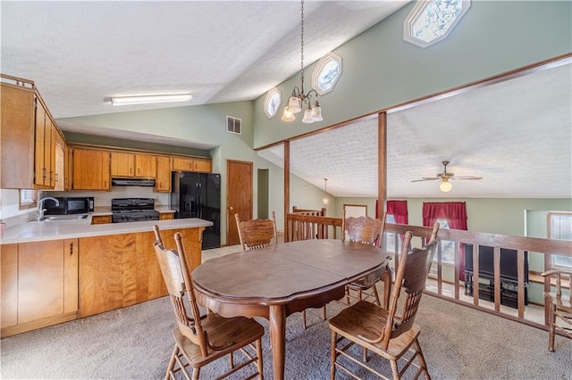 dining space with visible vents, light colored carpet, a textured ceiling, high vaulted ceiling, and ceiling fan with notable chandelier