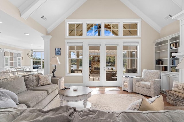 living room featuring a towering ceiling, an inviting chandelier, beam ceiling, and hardwood / wood-style flooring