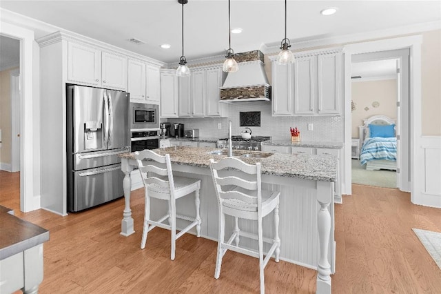 kitchen with pendant lighting, premium range hood, stainless steel appliances, and white cabinetry