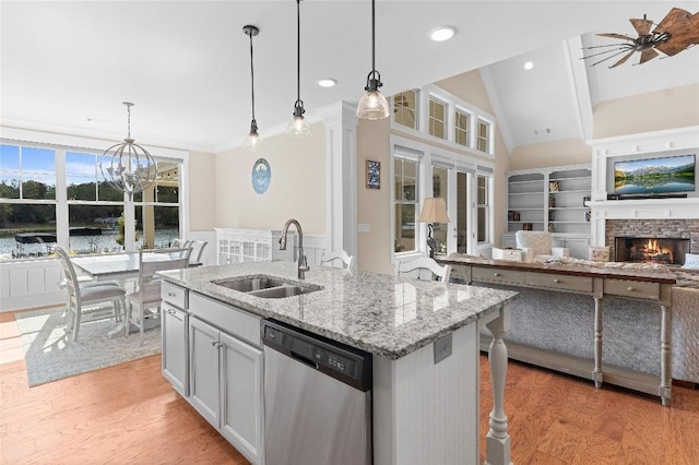 kitchen featuring a kitchen island with sink, dishwasher, sink, and pendant lighting