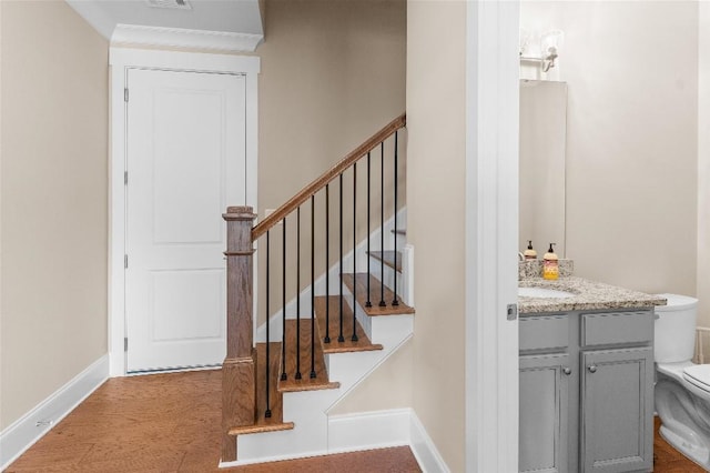 stairs featuring indoor wet bar, wood-type flooring, and crown molding