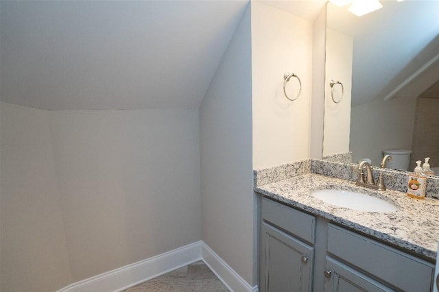 bathroom featuring toilet, vanity, and lofted ceiling