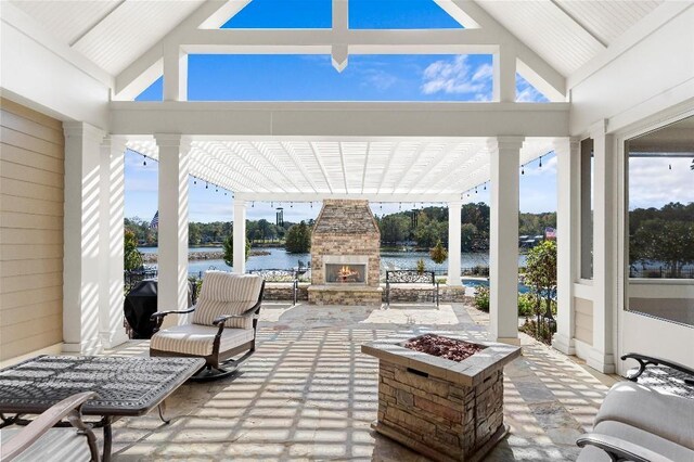 view of patio / terrace featuring an outdoor stone fireplace, a water view, and an outdoor fire pit