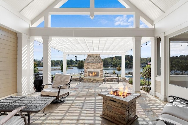 view of patio / terrace featuring an outdoor stone fireplace, a fire pit, and a water view