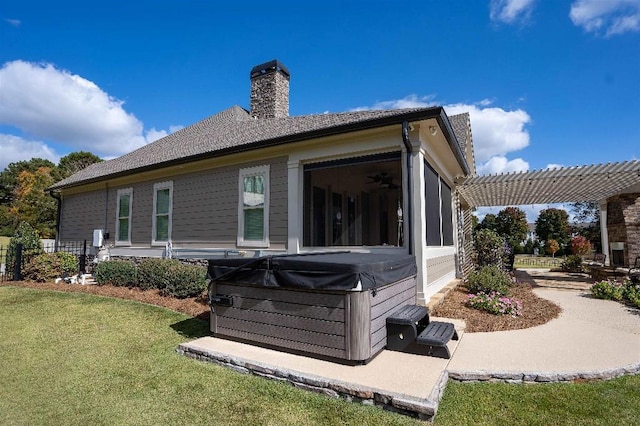 back of house featuring a sunroom, a hot tub, a yard, and a pergola