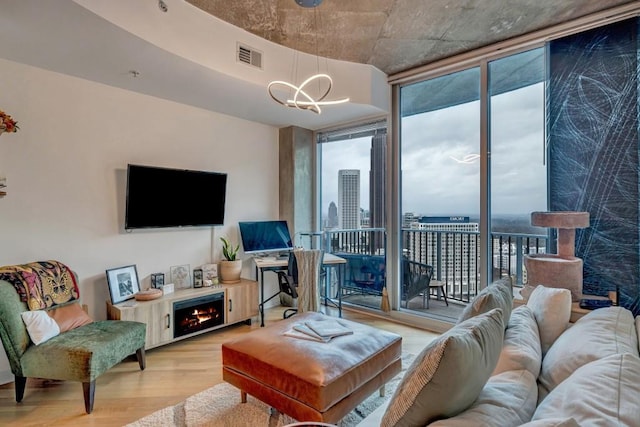 living room with light hardwood / wood-style flooring, plenty of natural light, floor to ceiling windows, and a notable chandelier