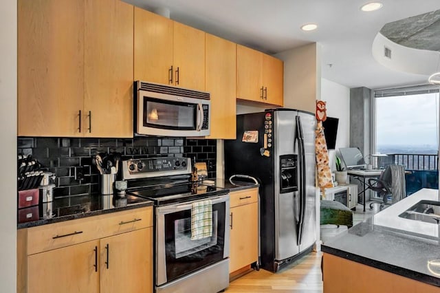 kitchen with appliances with stainless steel finishes, decorative backsplash, light brown cabinetry, and light hardwood / wood-style flooring