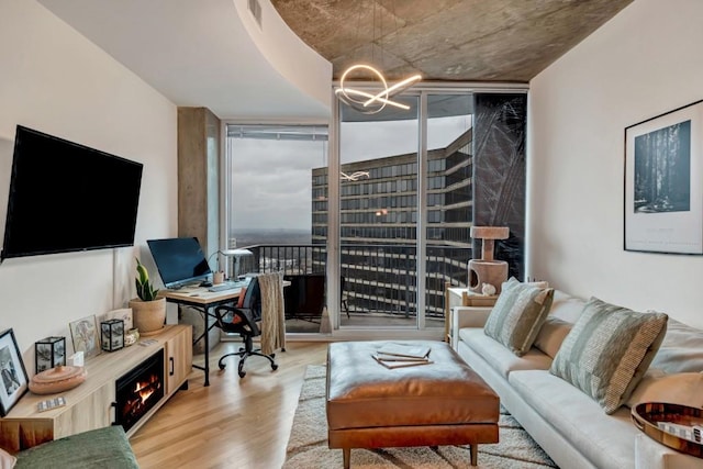 living room with a wealth of natural light, light hardwood / wood-style flooring, floor to ceiling windows, and a chandelier