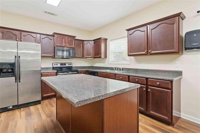 kitchen featuring light wood-type flooring, appliances with stainless steel finishes, sink, and a center island