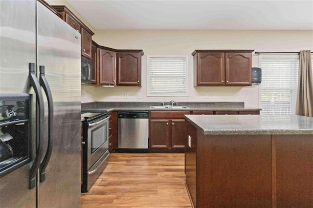 kitchen with appliances with stainless steel finishes, sink, dark brown cabinets, and light hardwood / wood-style floors